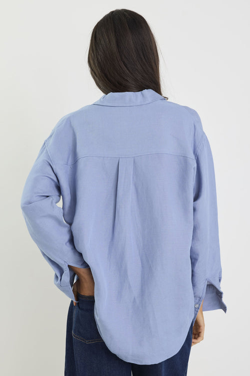 Person wearing a light blue shirt and dark jeans on a white background