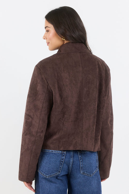 Person wearing a brown suede jacket and blue jeans on a white background
