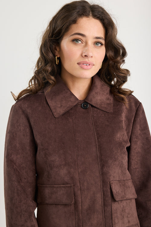 Woman wearing a brown suede coat against a white background