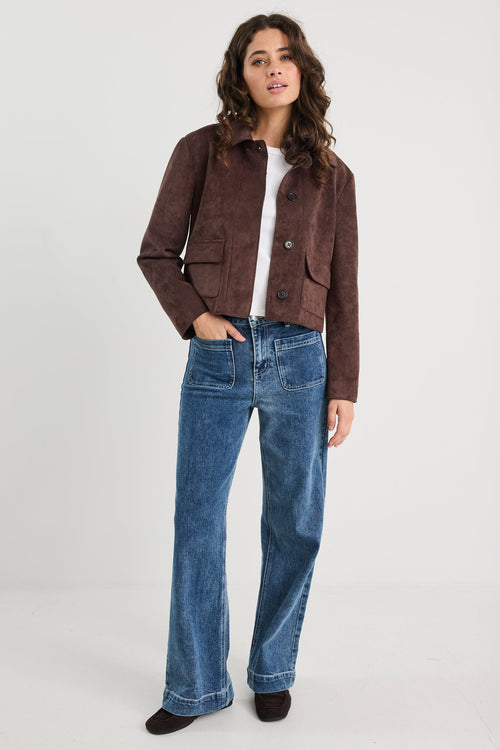 Woman wearing a brown jacket and blue jeans on a white background