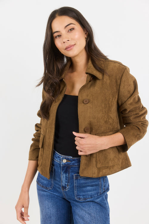 Woman wearing a brown jacket and blue jeans on a white background
