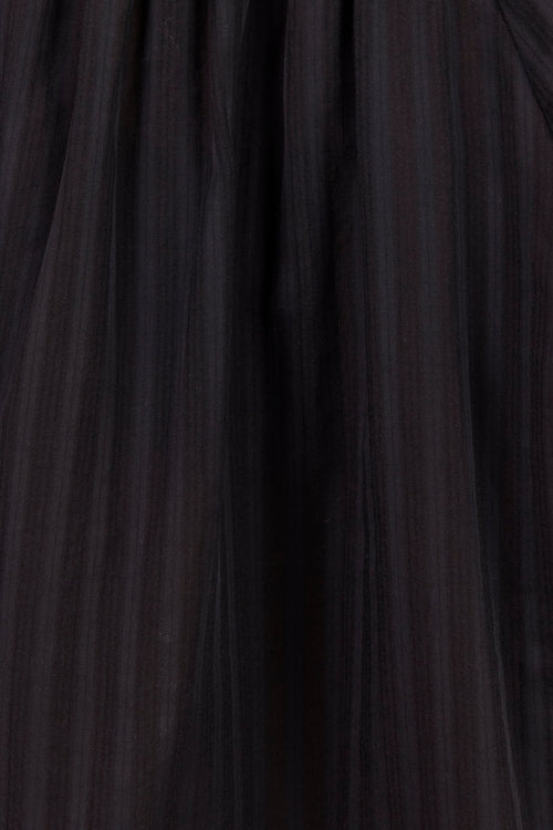 Close-up of a black pleated fabric garment, showing gathered texture and vertical pleats.