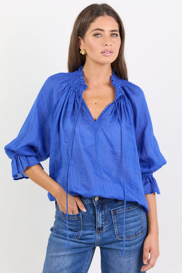 Woman wearing a blue blouse with ruffled sleeves on a white background
