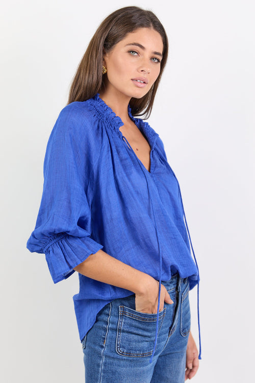 Woman wearing a blue blouse and jeans on a white background