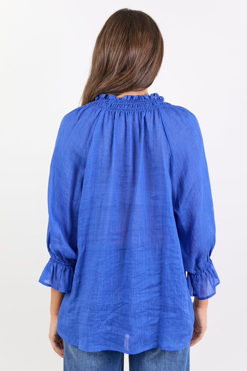 Woman wearing a blue blouse with ruffled sleeves on a white background