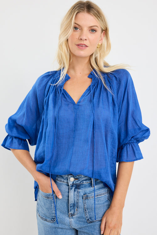 model wears a blue linen blouse with blue jeans