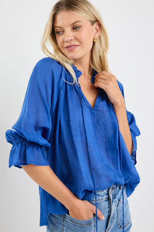 model wears a blue linen blouse with blue jeans
