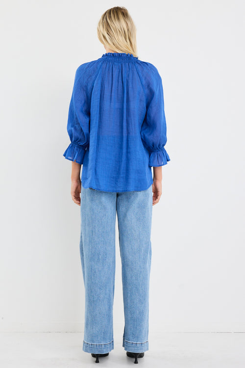 model wears a blue linen blouse with blue jeans