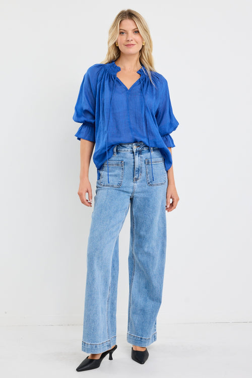 model wears a blue linen blouse with blue jeans