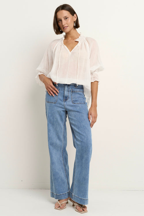 model wears a white blouse with light blue jeans