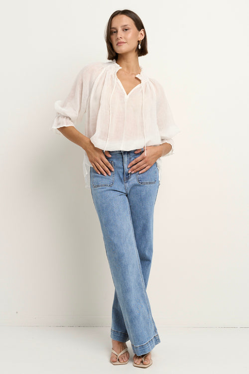 model wears a white blouse with light blue jeans