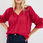 model wears a red blouse with denim jeans