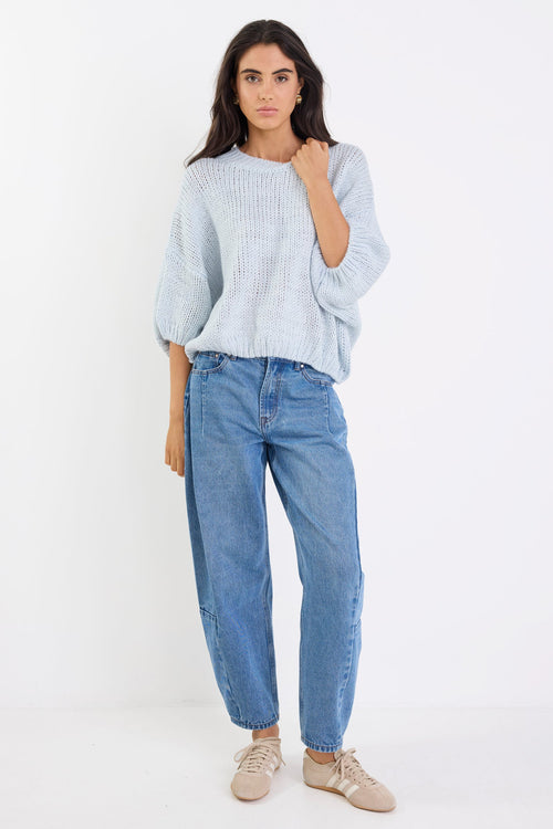 Woman wearing a light blue sweater and jeans on a white background
