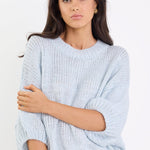 Woman wearing a light blue sweater and jeans on a white background