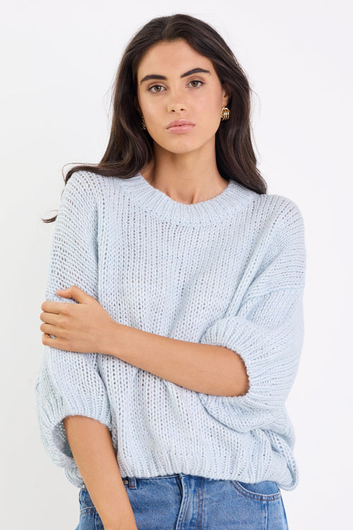 Woman wearing a light blue sweater and jeans on a white background