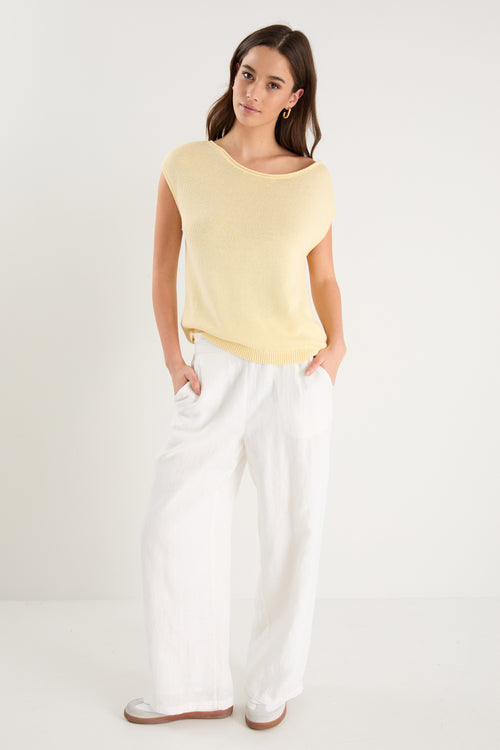 The model wears a yellow knit top with white pants