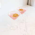 Fiesta Pink Swirl Stripe Martini Glass in clear glass with delicate pink spiral detailing, styled on a light marble surface.