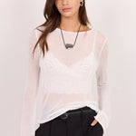 A woman modeling a white sheer long-sleeve mesh top over a white lace bralette, paired with black wide-leg pants, against a plain light background.