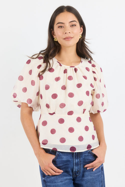 Woman wearing a polka dot blouse with puffed sleeves on a white background