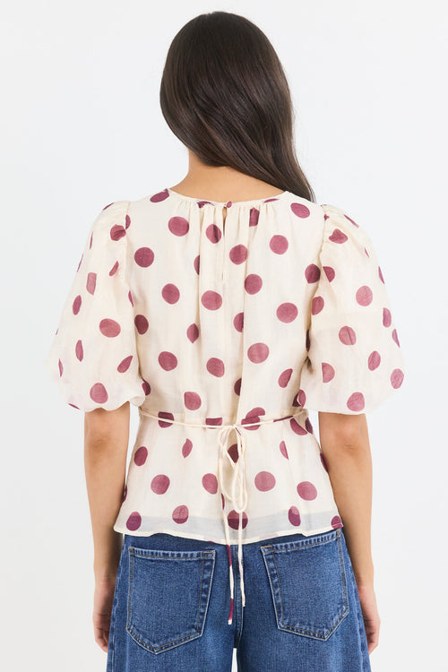 Woman wearing a polka dot blouse and jeans on a white background