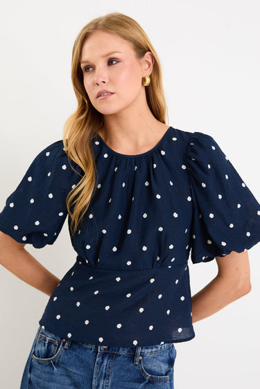 Model wearing a navy short sleeve bubble-sleeve top with white polka dots