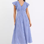 Woman wearing a blue gingham midi dress with a V-neck, button-down front, and fluted sleeves, paired with nude sandals.
