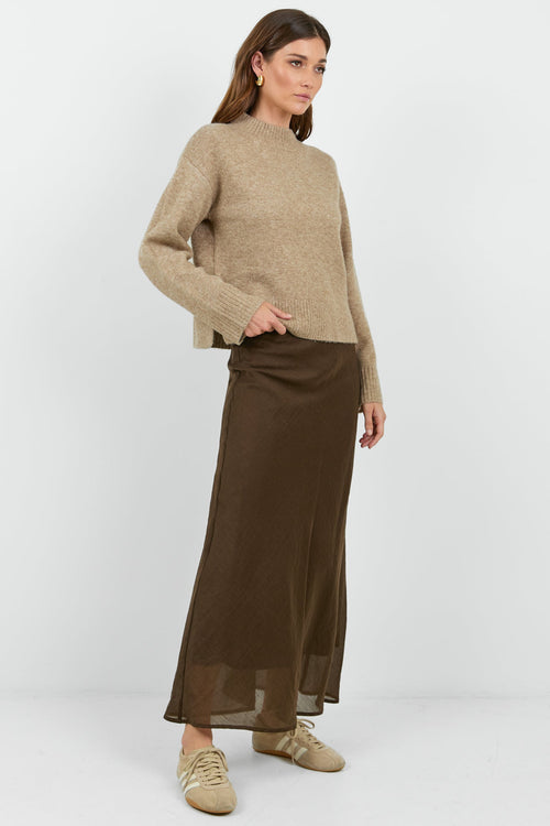 Woman wearing a beige sweater on a white background