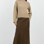 Woman wearing a beige sweater and brown skirt on a white background
