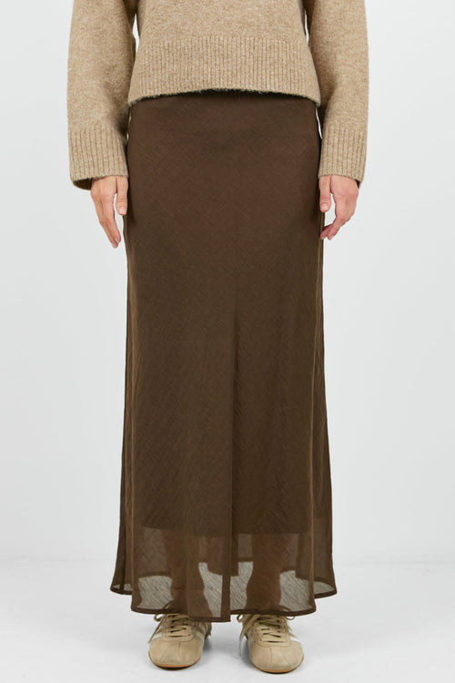 Person wearing a beige sweater and brown skirt on a white background