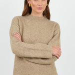 Woman wearing a beige sweater against a white background
