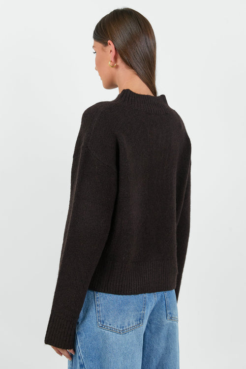 Person wearing a black sweater and blue jeans on a white background