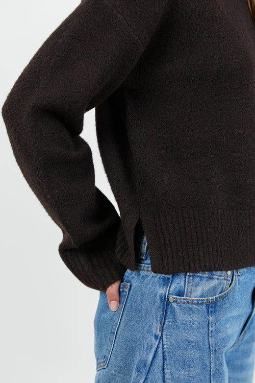 Person wearing a black sweater and blue jeans on a white background