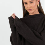 Woman wearing a black oversized sweater against a white background