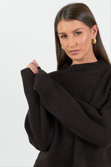 Woman wearing a black oversized sweater against a white background