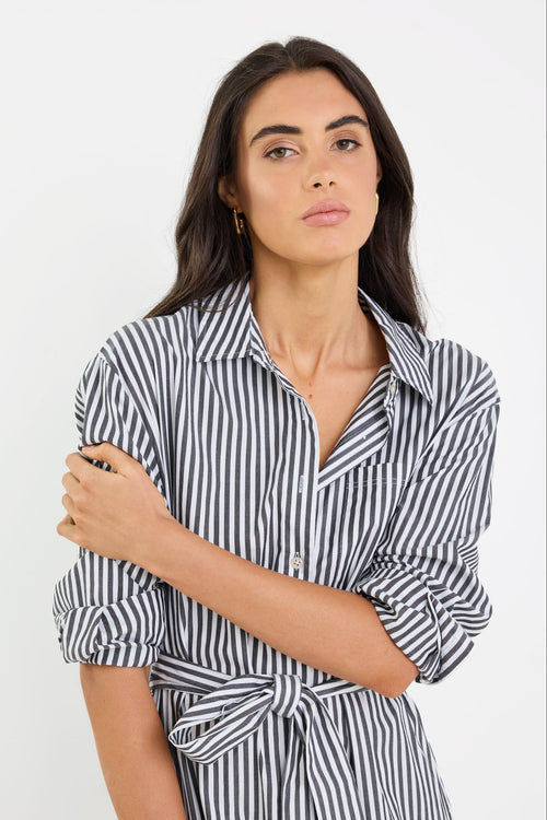 Woman wearing a black and white striped shirt dress against a plain background