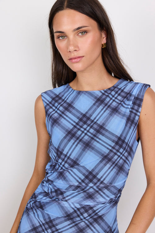 Woman wearing a blue plaid dress against a plain background