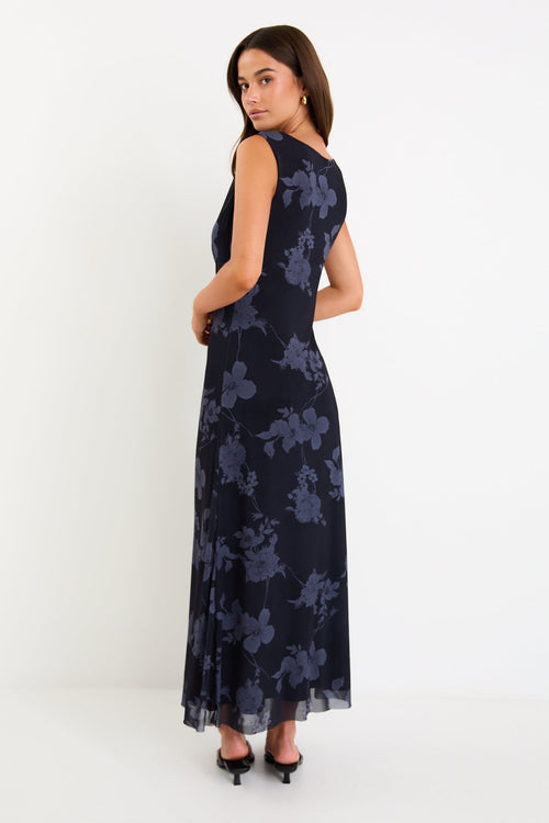 Model wearing a sleeveless midnight floral mesh maxi dress with gentle gathering at the waist and a slim, draped silhouette.