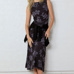Woman wearing a floral dress against a white wall