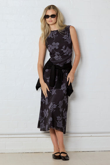 Woman wearing a floral dress against a white wall