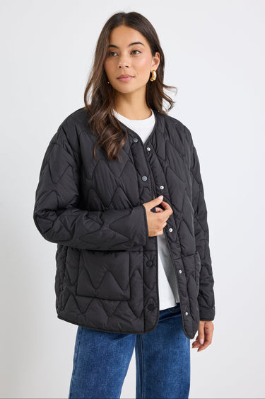 Woman wearing a black quilted jacket on a white background