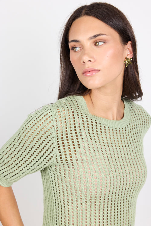 Woman wearing green knit tee and blue denim jeans on white background.