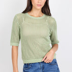 Woman wearing green knit tee and blue denim jeans on white background.