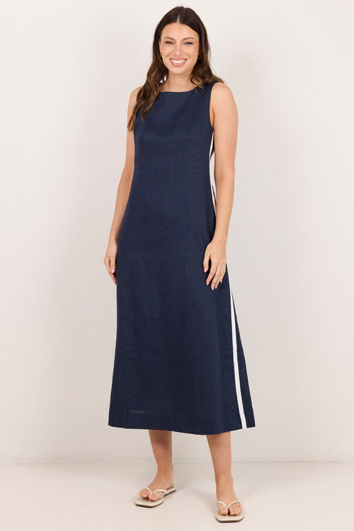 A woman modeling a sleeveless navy midi dress with white side stripes, standing against a plain off-white studio background.