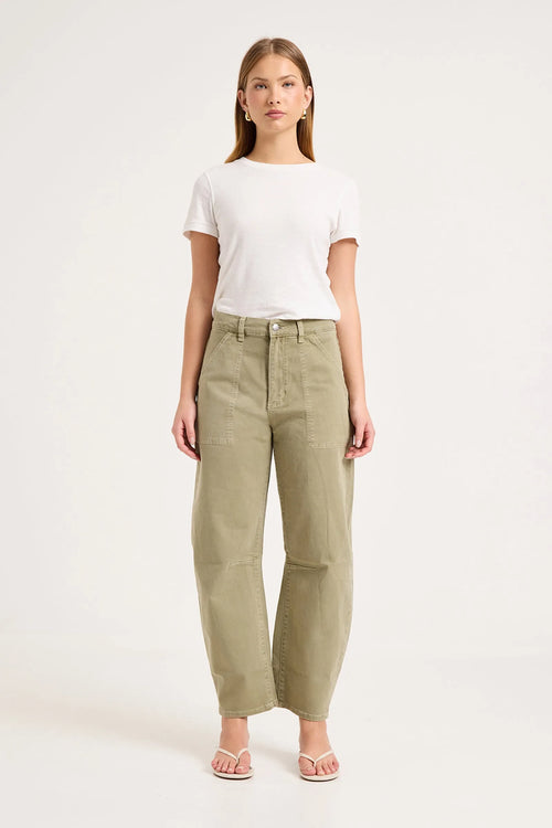 A woman modeling a pair of high-waisted, wide-leg olive green trousers, styled with a white t-shirt and light pink sandals against a plain white studio background.