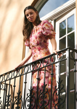 Woman in a floral dress standing on a balcony