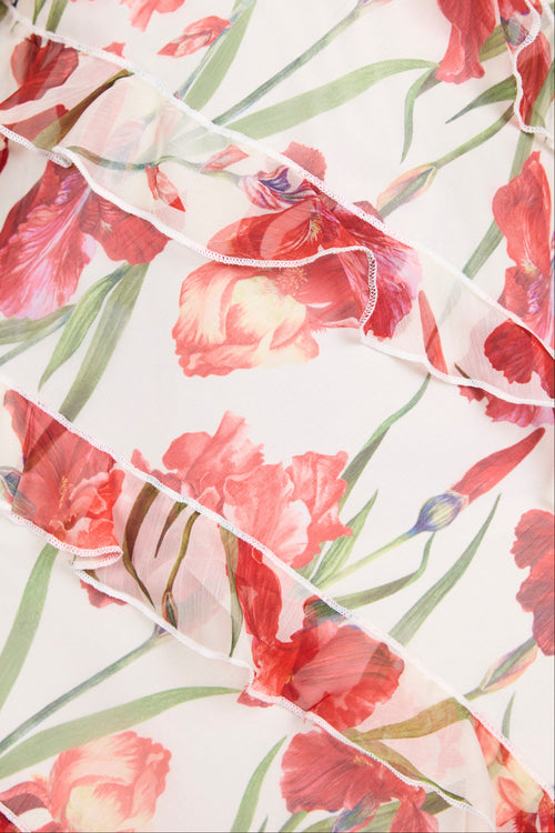 Close-up of a white ruffled sleeveless dress featuring a vibrant red and green floral print.