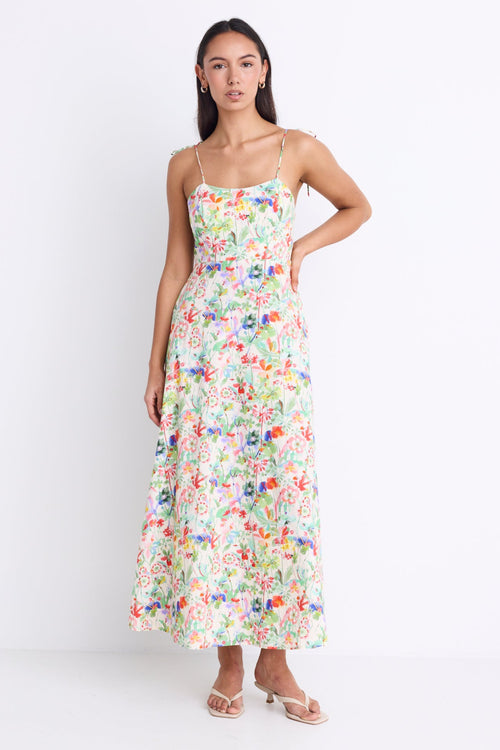 Model wearing a floral strappy maxi dress with a tie detail and shirred back.
