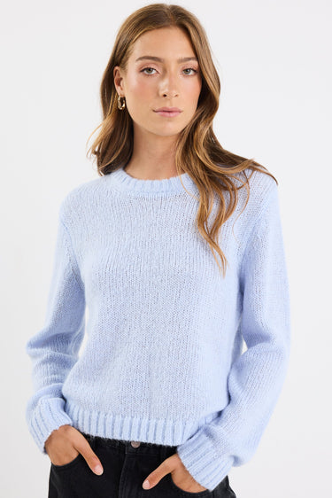 Woman wearing a light blue sweater against a white background
