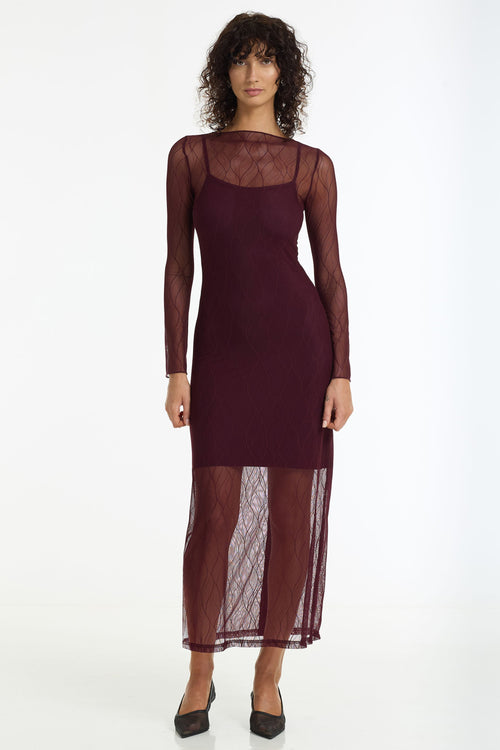 Woman wearing a burgundy dress with sheer sleeves on a white background