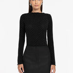 Woman wearing a black long-sleeve top with a pattern and a black skirt on a white background